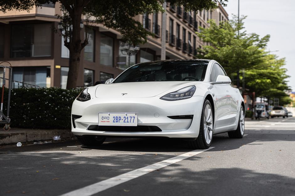 Een elektrische auto die wordt gebruikt als thuisbatterij met zonnepanelen op het dak en een huis op de achtergrond.